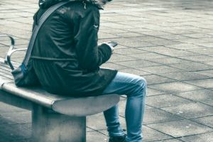 a sitting man watch his smartphone